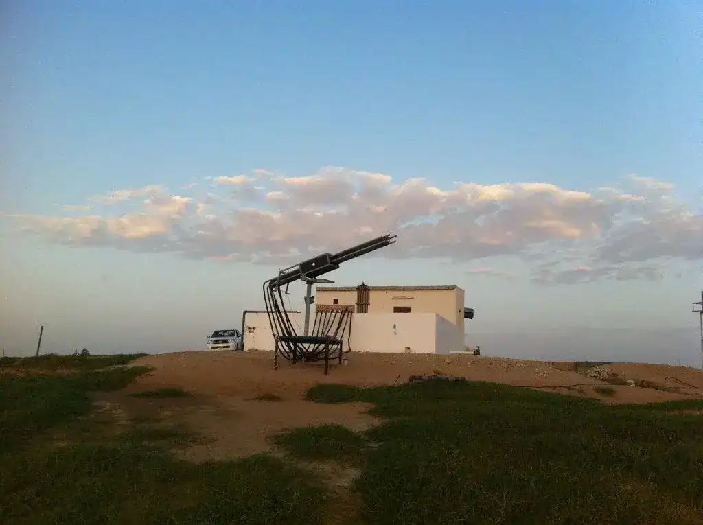 Alt-Text: Wüstenbegrünungsprojekt mit Muschelstruktur in der Wüste bei Sonnenuntergang.