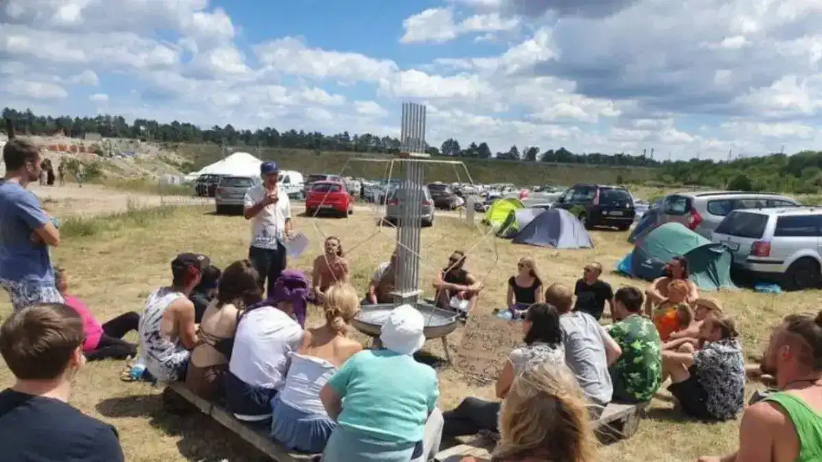 Menschen bei einer Informationsveranstaltung zum Desert Greening im Freien, umgeben von Autos und Zelten.
