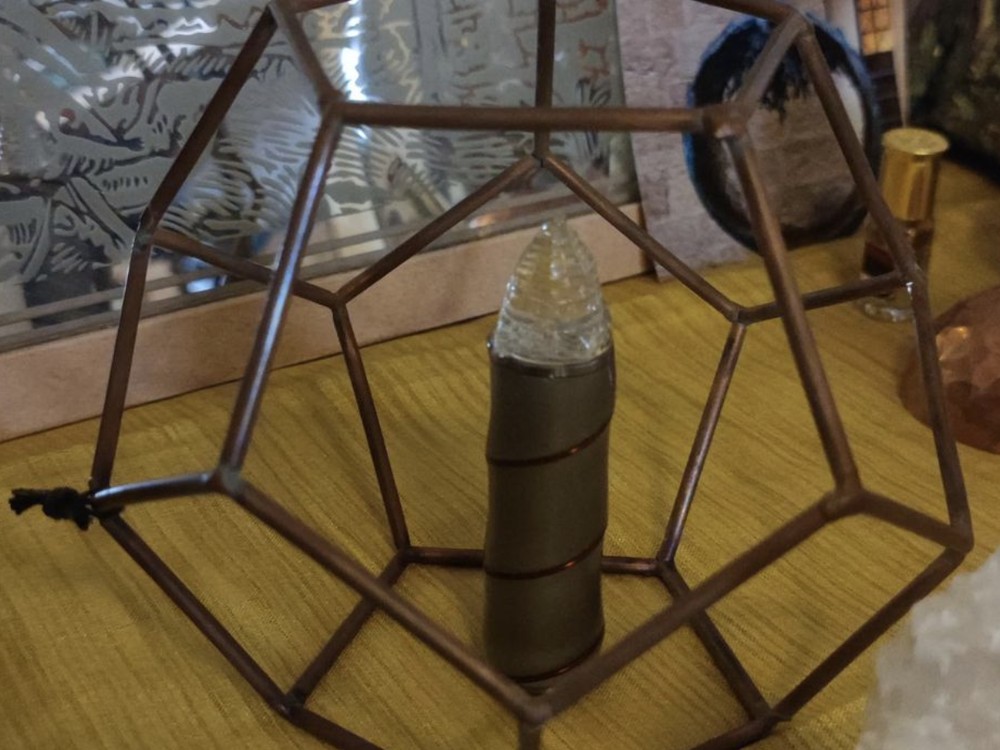 Dodekaeder aus Kupfer und Glas mit Kristall im Inneren, auf einem Tisch
