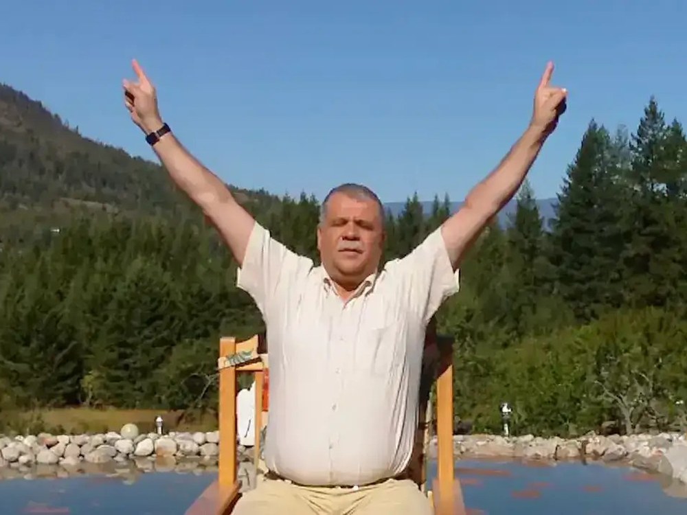 Madjid Abdellaziz steht mit erhobenen Armen vor einer Berglandschaft