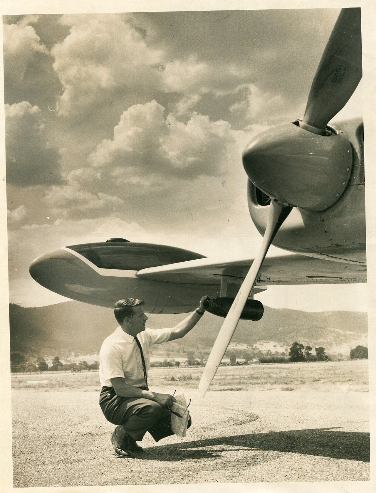 Ein Mann lädt 1966 in Corryong, Victoria, eine Silberiodid-Patrone in den Tragflächenbehälter einer Cessna 410