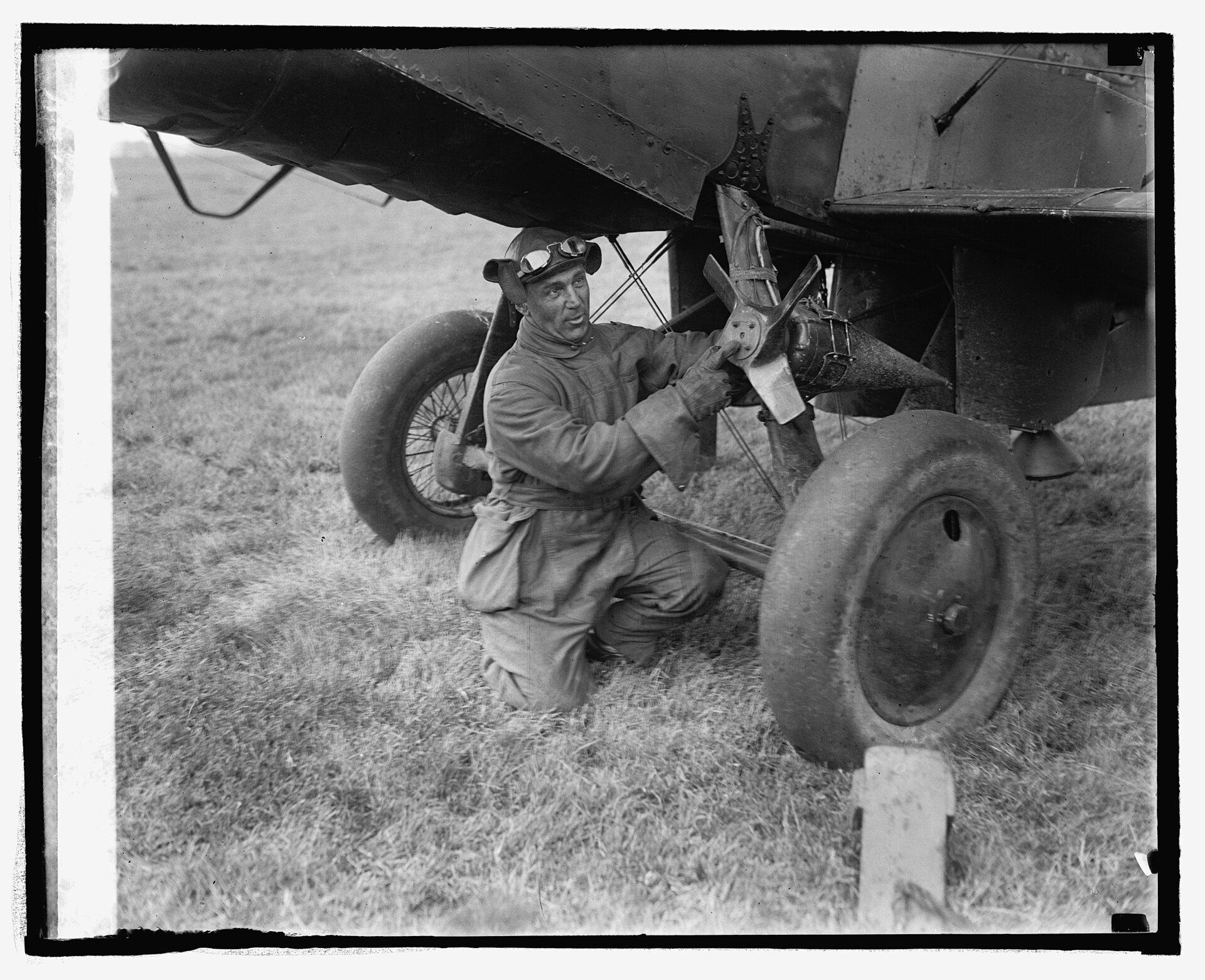 Mechaniker montiert 1924 eine raketenförmige Regenmach-Vorrichtung am Fahrwerk eines Flugzeugs auf dem Bolling Field bei Washington